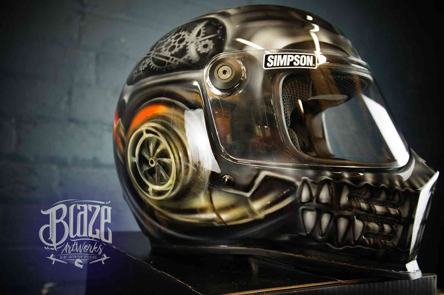 Custom painted black motorcycle helmet featuring detailed steampunk skull design with mechanical gears, bronze and orange airbrushed artwork on glossy finish